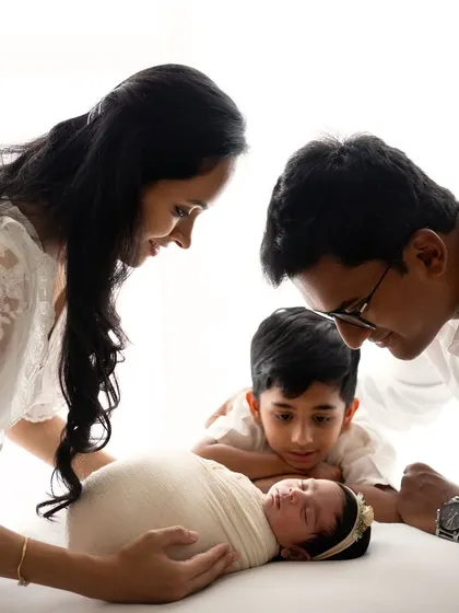 The whole family admiring their newest member. A beautiful moment with mom, dad, and big brother looking down at the sleeping newborn.