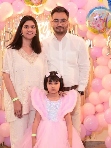 A beautiful family portrait in front of a pink balloon wall. The birthday girl looks like a true princess in her special dress.
