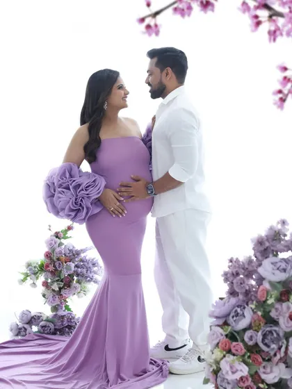 A regal maternity portrait featuring a stunning lavender gown and a floral arch. This studio setup is perfect for clients who want a touch of royal elegance for their shoot.