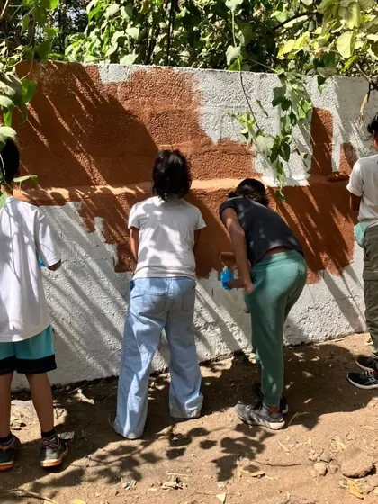 A team of young volunteers works together, each playing a part in repainting a wall at the animal shelter.