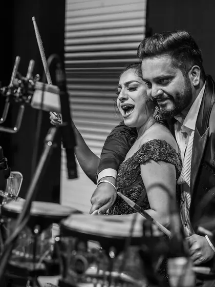 A beautiful black and white candid of the couple sharing a moment at the drum set during their sangeet. It's a unique and intimate party shot.