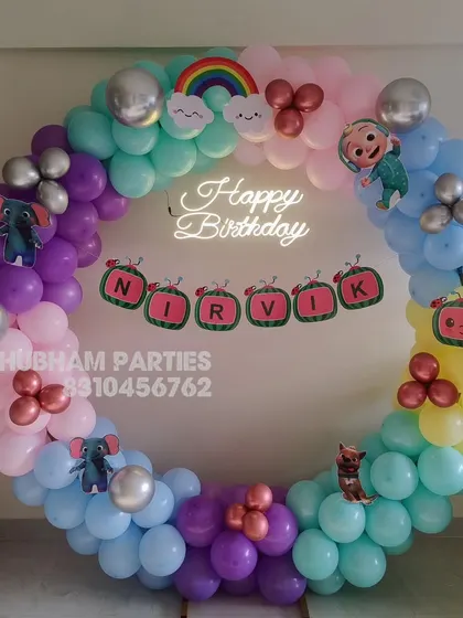 A Cocomelon themed ring decoration with a "Happy Birthday" neon sign and personalized name banner.