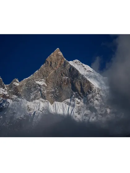 A close-up view of a Himalayan peak shrouded in clouds, showing the raw and powerful beauty of the world's highest mountains.
