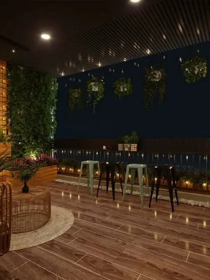 This balcony is designed for evening entertainment, with a bar-height counter and stools overlooking the city. The warm lighting and green wall create a cozy and inviting atmosphere.