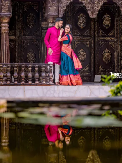 I love playing with creative compositions like this reflection shot. It adds an artistic, symmetrical element to this beautiful portrait of a couple in traditional attire, set against a grand backdrop.