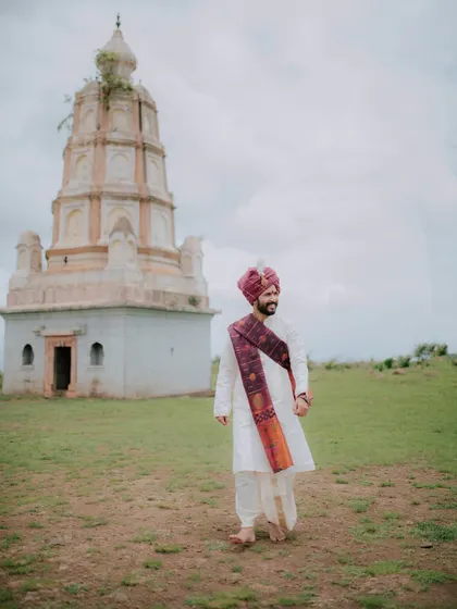 A walking shot of the groom in his traditional attire, captured at a historic location.