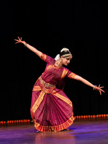 A wide, graceful pose from a solo recital, showcasing the dancer's command of the stage. The arms are extended, creating a beautiful line.