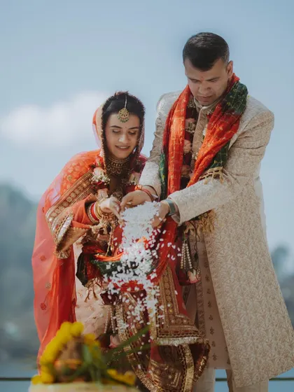 The couple participates in a traditional ritual during their Hindu wedding ceremony, a moment of shared devotion.