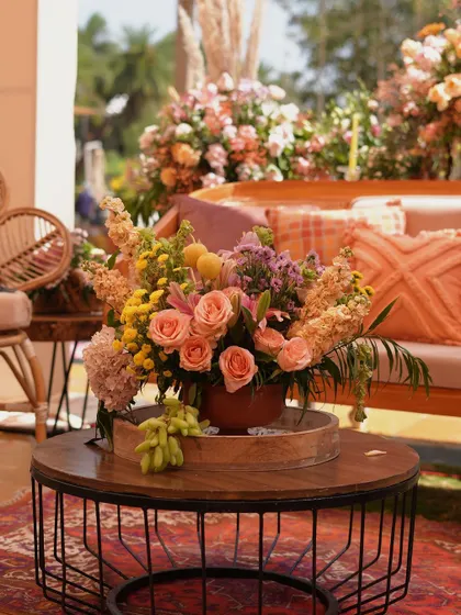 A cozy seating area with pastel sofas, rustic-chic tables, and vibrant floral centerpieces, creating a perfect garden party atmosphere.