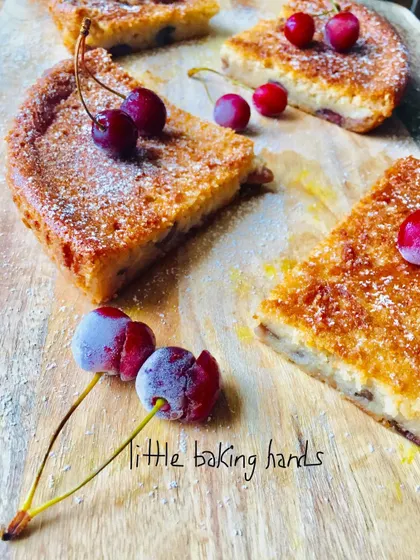 A vegan vanilla cherry lime cake made with whole wheat flour. The cake is sliced to show the lovely, light crumb with pieces of cherry baked inside.