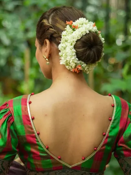A green and red checked blouse with a deep V-back and puffed sleeves. The back is adorned with delicate bead detailing.