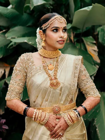 This bride is the epitome of elegance in her off-white and gold wedding attire. The custom-designed blouse and traditional jewelry create a timeless and sophisticated look.