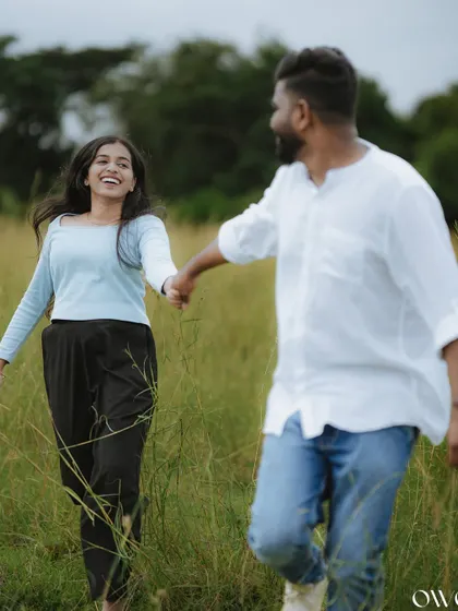 A candid shot of a couple holding hands and laughing as they run through a field, perfectly capturing their natural chemistry.