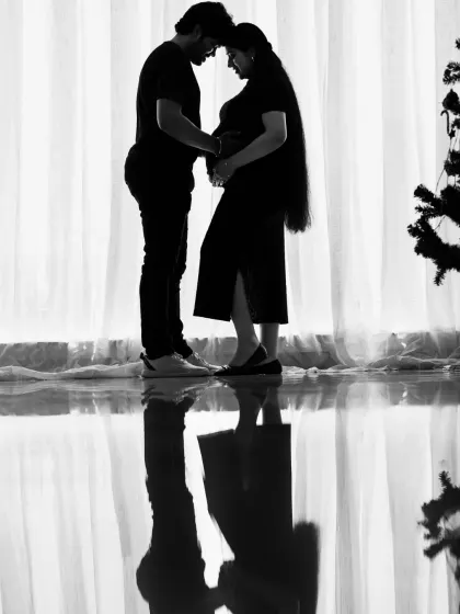 A powerful silhouette shot of a couple against a bright window. This black and white photo with its reflection creates a dramatic and artistic portrait of their shared journey.