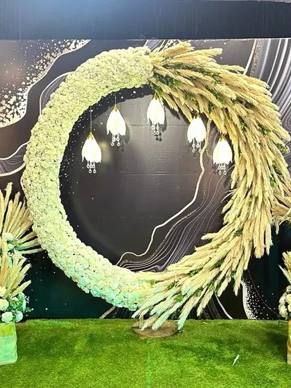 A bohemian-inspired photo booth featuring a large crescent of white florals and dried pampas grass. The design is modern, earthy, and incredibly chic.