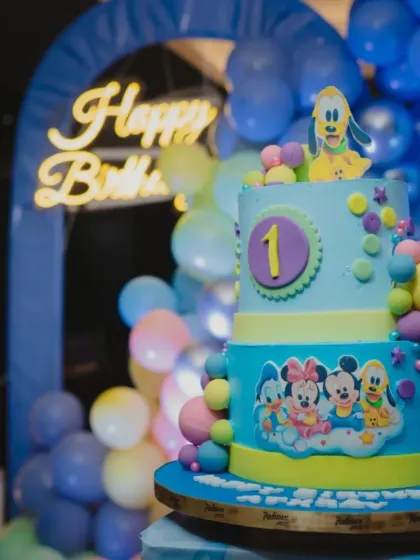 The cake is the centerpiece! This beautiful two-tier cake perfectly matches the Mickey and Friends theme, sitting in front of our custom balloon backdrop.