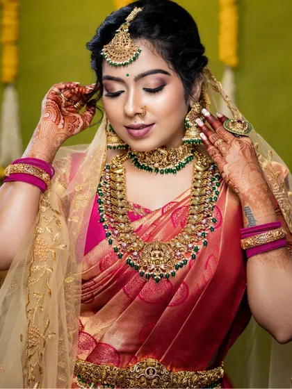 A beautiful close-up showing the intricate details of the necklace, jhumkas, and maang tikka. The green stones provide a lovely pop of color.