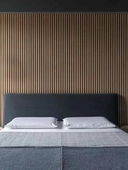 A frontal view of the bed, showing the simple, clean lines and the warmth of the slatted wood headboard.