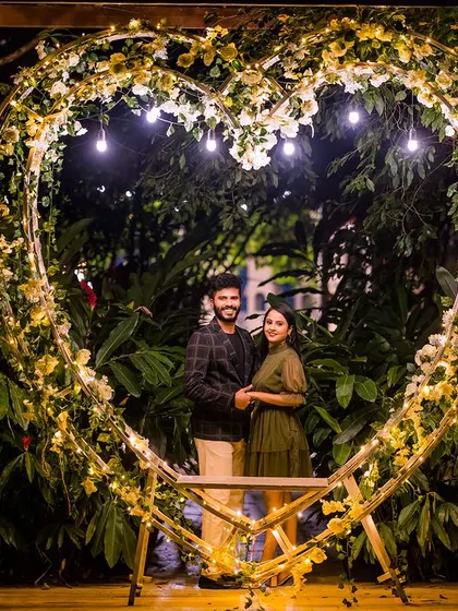A romantic portrait inside a heart-shaped arch decorated with flowers and lights. This setup provides a beautiful, natural frame for the couple, highlighting their connection.