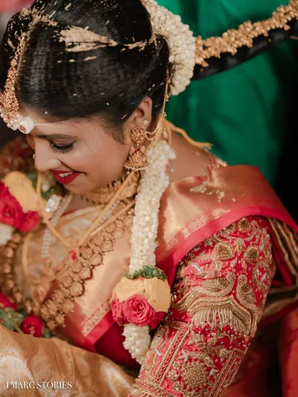 Our client Rakshitha on her wedding day, wearing a traditional red and gold saree with a heavily embroidered custom bridal blouse.