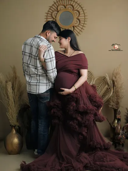 An intimate pose showing the couple's connection. They stand forehead-to-forehead, wrapped in an embrace, with the flowing maroon gown adding a touch of romance to this studio shot.