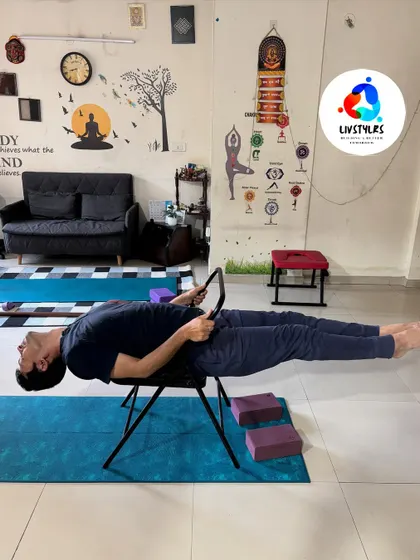 I'm demonstrating an advanced core and back-strengthening pose using a yoga chair. This shows how props can be used to create challenging and unique variations of traditional poses.