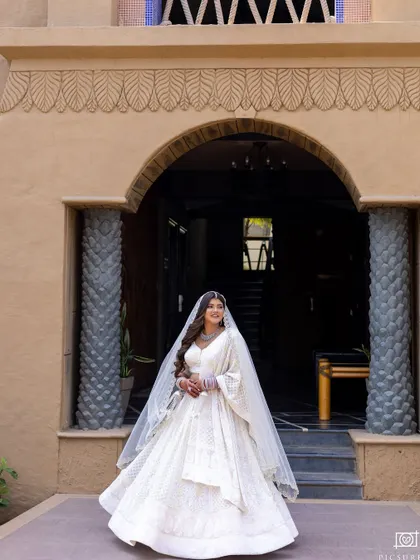 A stunning architectural shot. The bride stands out beautifully against the backdrop, her white lehenga looking crisp and elegant.