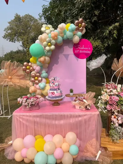 A detailed look at a pink-themed 10th birthday party table, complete with a beautiful cake, floral arrangements, and a custom backdrop.