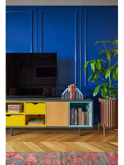 A detail of the TV console against the blue paneled wall, showcasing how we use pops of color, like the yellow drawers, to add a playful touch.
