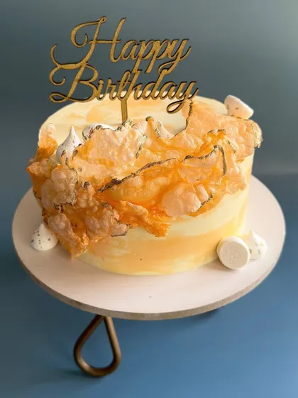 This custom birthday cake combines a soft yellow watercolor finish with abstract, burnt-orange wafer paper sails and small meringue kisses. The flavor inside is my seasonal Mango Vanilla.