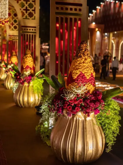 An impression of the Hindu 'Kalasha Sthapana', this entrance arrangement symbolizes an auspicious beginning. Crafted from marigolds and roses in a golden urn, it is a beautiful and meaningful welcome for guests.