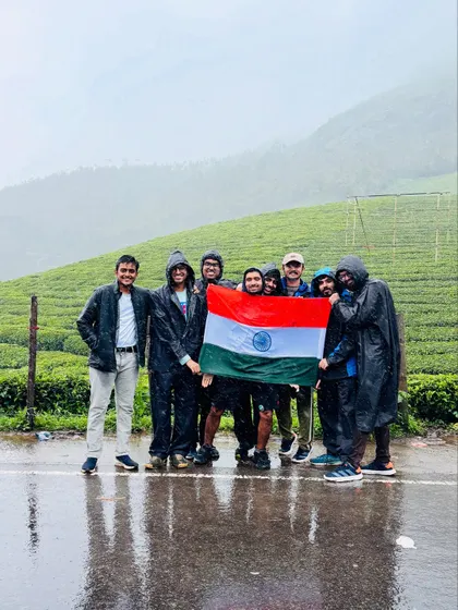 A group of friends holding the Indian flag in the rainy tea plantations of Munnar.