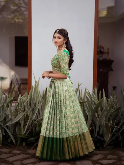 A side profile of the pista green half saree, showing the elegant drape of the dupatta and the detailed craftsmanship of the Kanchipuram silk lehenga.
