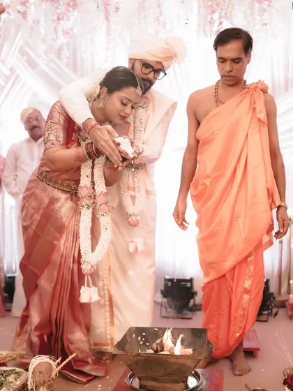 The couple performs the laja homa ritual, offering puffed rice to the sacred fire during their wedding ceremony.