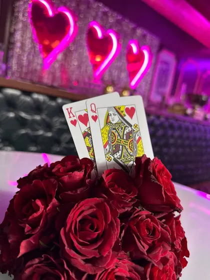 A playful detail for a casino or love-themed party, with a King and Queen of Hearts card tucked into a bouquet of red roses.