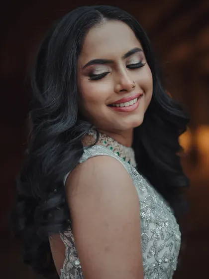 A portrait of a glamorous and glowing bride. The soft, voluminous curls and shimmering eye makeup create a look that is both romantic and sophisticated.