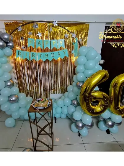 A 60th birthday celebration with a half-arch of pastel blue and silver balloons and large gold foil number balloons.