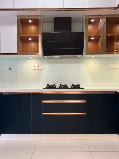 A full view of this U-shaped kitchen with navy blue and white cabinets, accented with rose gold handles and trim. The design is both bold and timeless.
