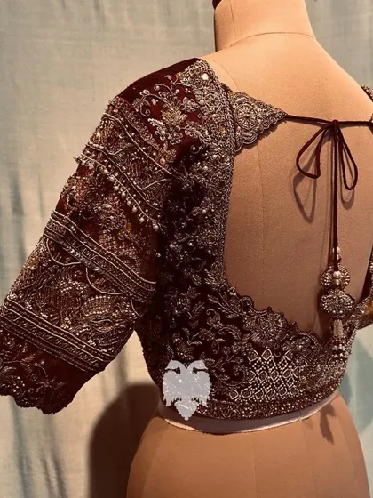 The dramatic cut-edge back of the maroon blouse, adding a touch of modern drama.