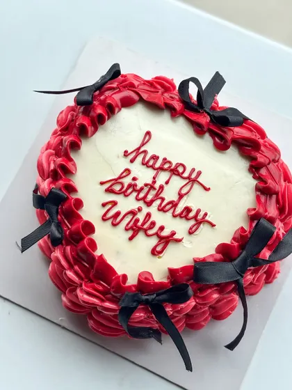 I love a good vintage buttercream and bow moment. This design features rich red buttercream piping with delicate black bows, perfect for a romantic and stylish "happy birthday wifey" cake.