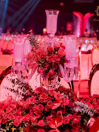 A close-up of the tablescape, featuring a crystal candelabra centerpiece overflowing with red roses and foliage. Every detail was chosen to reinforce the theme of passionate, luxurious romance.