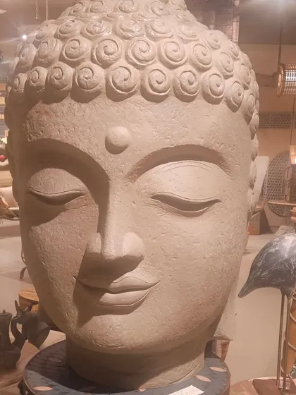 Another view of the large, serene Buddha head sculpture, a popular choice for creating a tranquil and meditative atmosphere in outdoor spaces.