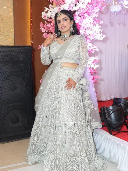 A happy client posing in a stunning silver-grey embroidered lehenga at an event.
