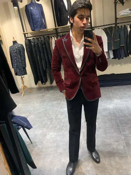 A rich maroon velvet blazer is a versatile addition to any formal wardrobe. Here, it's styled with a white shirt and black trousers for a classic cocktail party look.