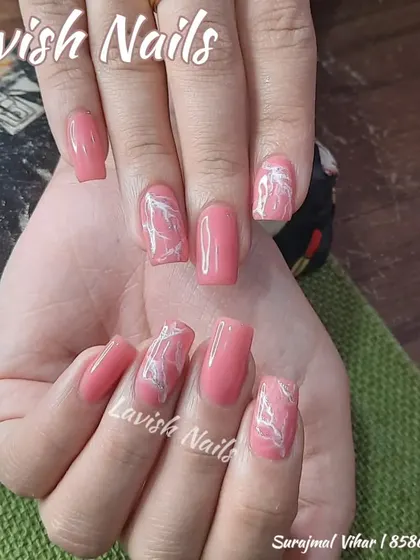 A simple yet chic design with pink polish and accent nails featuring a white marble or smoke effect.