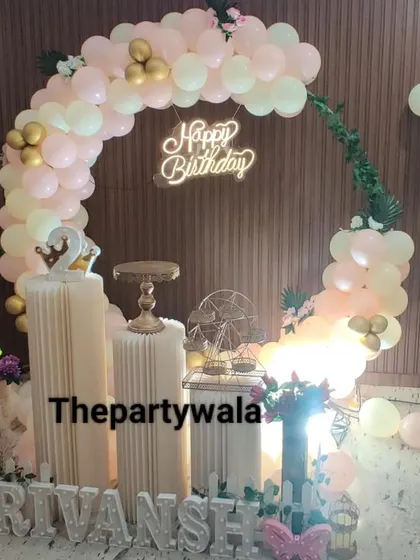 A peach and white balloon ring with a 'Happy Birthday' neon sign.