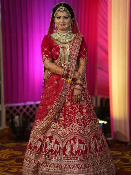 A full-length view of our bride in her magnificent red lehenga. The entire look, from the makeup to the styling, comes together to create a picture of pure bridal elegance.