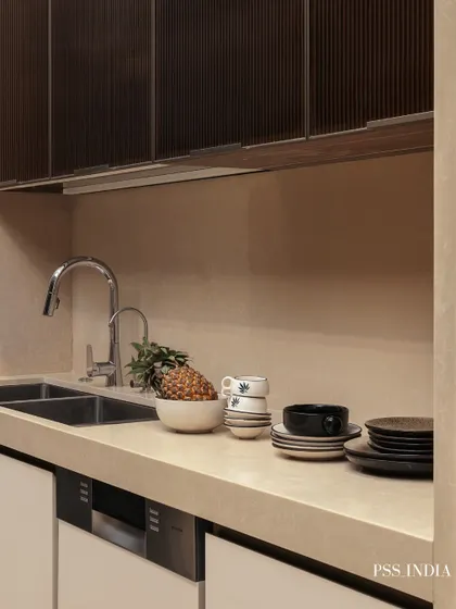 Even the sink area can be beautifully styled. Here, stacked ceramics, a bowl of fruit, and a small plant add color and texture to the countertop, turning an everyday utility space into a curated moment.