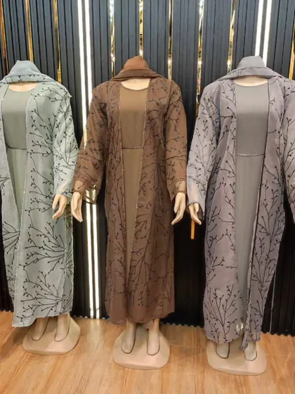 These three piece abaya sets come with an inner dress and a sheer outer layer with delicate patterns. Available in soft green, brown, and grey, they offer a complete, coordinated modest look.