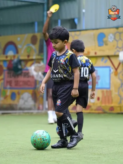 A young player with the ball at his feet, learning the basics of dribbling in a supportive environment.